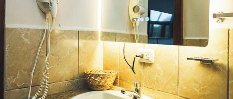 A bathroom with a granite countertop, a white sink, a hairdryer, and a mirror.