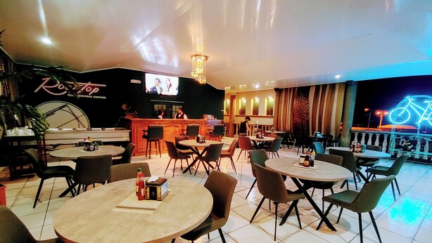 A restaurant with multiple tables and chairs, a bar area, and a television screen. - Hotel el Campanario (Comayagua)