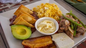A plate of food including eggs, beans, avocado, meat, and a small bowl of sauce. - Hotel el Campanario (Comayagua)