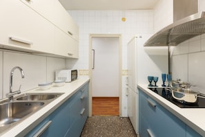 Una cucina moderna con elettrodomestici in acciaio inossidabile, un lavello doppio e mobili azzurri.