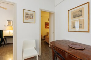 Une pièce avec une table en bois, une chaise blanche et des tableaux encadrés accrochés au mur.