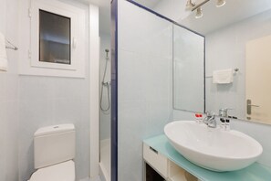 Un bagno moderno con un water bianco, una doccia con pareti in vetro e un lavandino capiente con uno specchio sopra.
