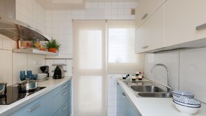 A modern kitchen with white cabinets, a stainless steel sink, and a black stove.