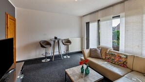 Un salon moderne comprenant un canapé, deux fauteuils, une table basse et un téléviseur.