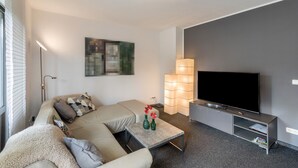 Un salon moderne avec un canapé, une table basse, un téléviseur à écran plat et une lampe.