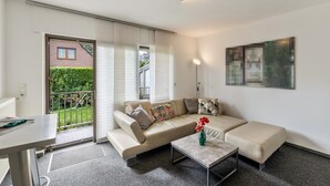 Un salon moderne avec un canapé, une table basse et une vue sur un jardin, accessible par une porte coulissante.