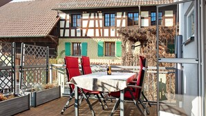 Une terrasse avec une table et des chaises, une vue sur un bâtiment traditionnel et une porte vitrée.