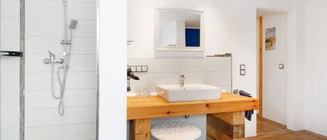 Un baño moderno con ducha, lavamanos y tocador de madera.