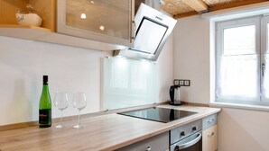 Une cuisine équipée d’une cuisinière intégrée, avec une bouteille de vin et deux verres posés sur le comptoir.