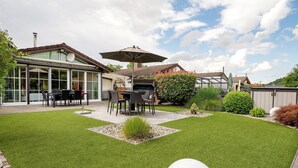 Un patio trasero con mobiliario exterior y un gran paraguas.