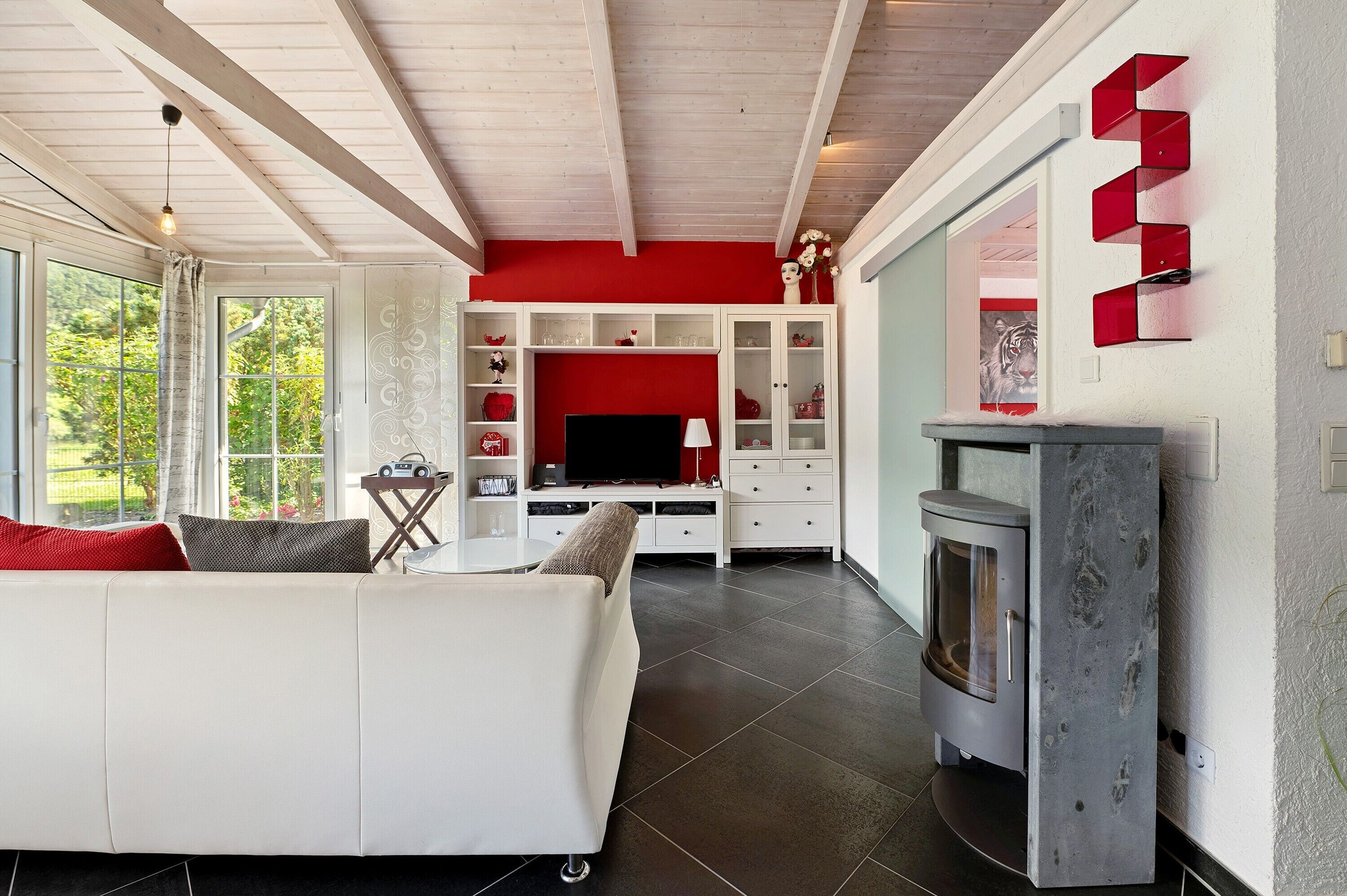 A modern living room with a white sofa, a fireplace, and a red accent wall.