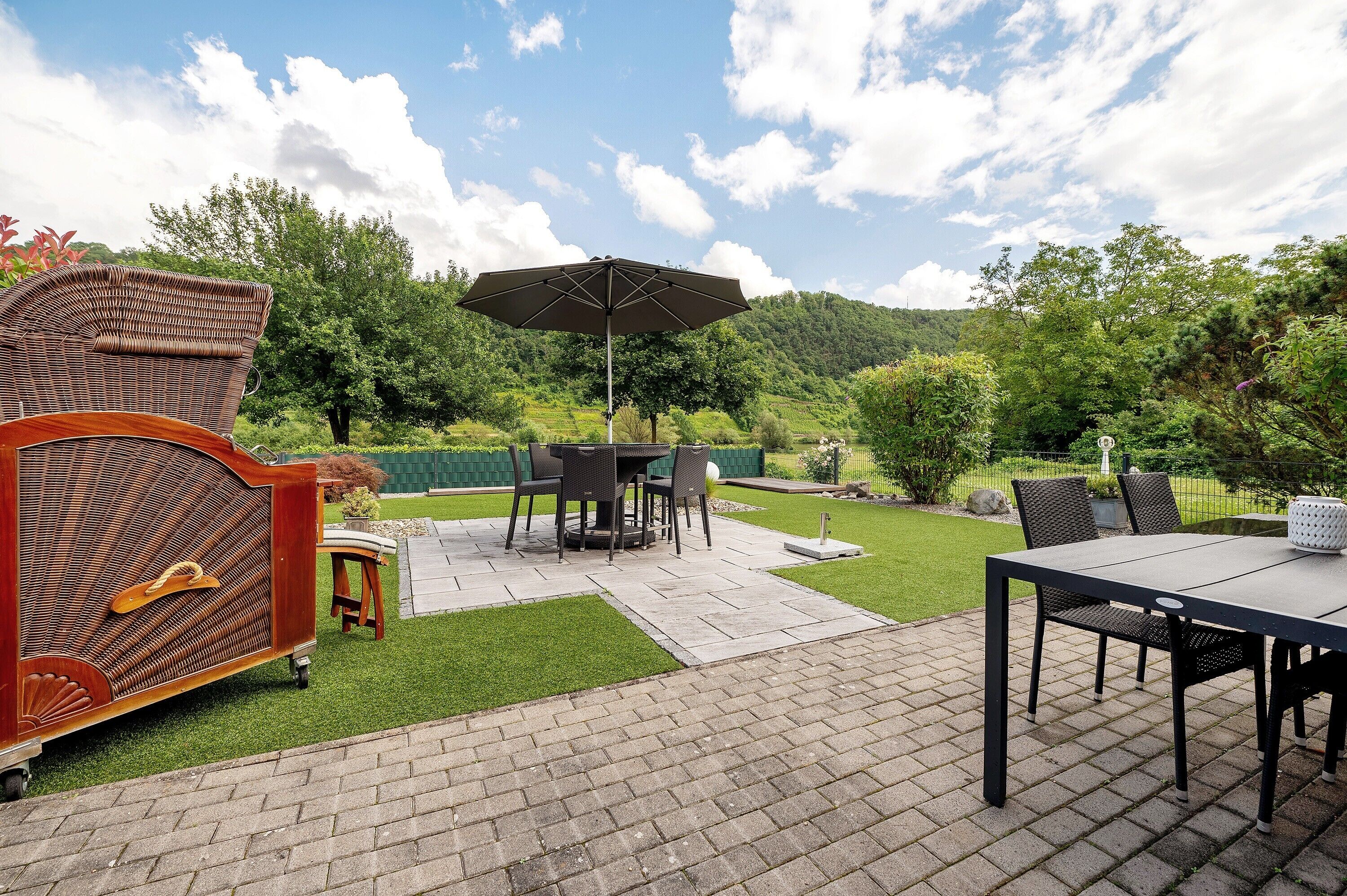 Une terrasse extérieure avec une table à manger, des chaises et un grand parasol.