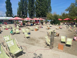 Une plage dotée de nombreuses chaises longues et de parasols, dont certains affichent les prix de location.