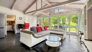 Un moderno salón con un sofá modular, una mesa de centro de cristal y ventanas amplias con vistas al exterior.