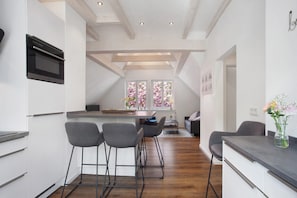 Una cucina moderna con forno a incasso, sgabelli da bar e vista su un'area pranzo tramite ampie finestre.