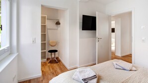 A bedroom with a bed, a chair, a TV, and a wardrobe. - Ferienwohnung Mühlengrund, 92 qm, 3 Schlafzimmer, max. 6 Personen (Kirchhundem)