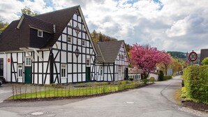 A traditional half-timbered building with a steep roof, a green door, and a small window. - Ferienwohnung Mühlengrund, 92 qm, 3 Schlafzimmer, max. 6 Personen (Kirchhundem)