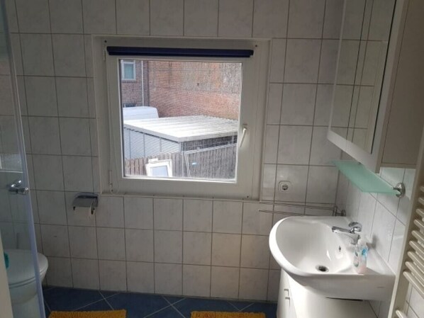 Un baño con ventana, lavamanos e inodoro.