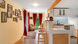 Une cuisine avec des meubles de rangement en bois, un évier et une fenêtre ornée de rideaux rouges.
