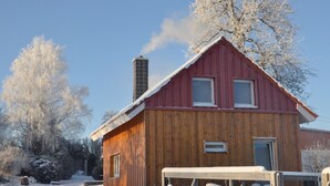 Une cabane en bois avec un toit rouge, une cheminée et une fenêtre.