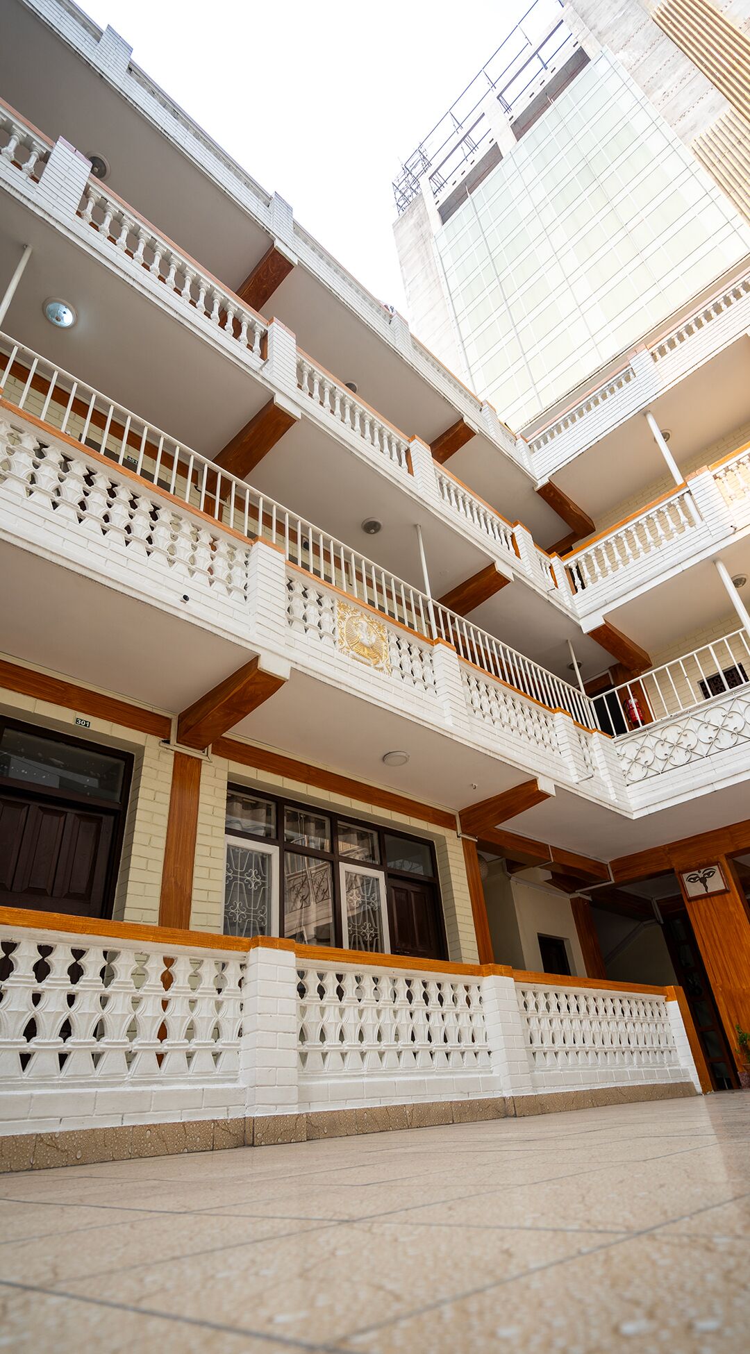 A multi-story residential building with balconies, wooden beams, and a tiled ground floor.