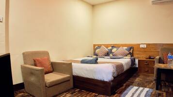 A bedroom with a bed, a chair, a nightstand, and a desk.