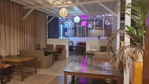 A modern interior with a dining area, sofas, and a view through a large window. - Hotel Shree Tara (Kathmandu)