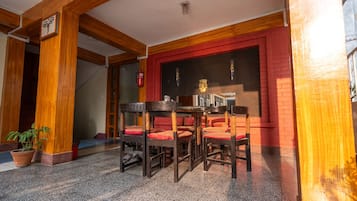 A traditional wooden interior with a red brick wall, a black and gold decorative panel, and a table with chairs.