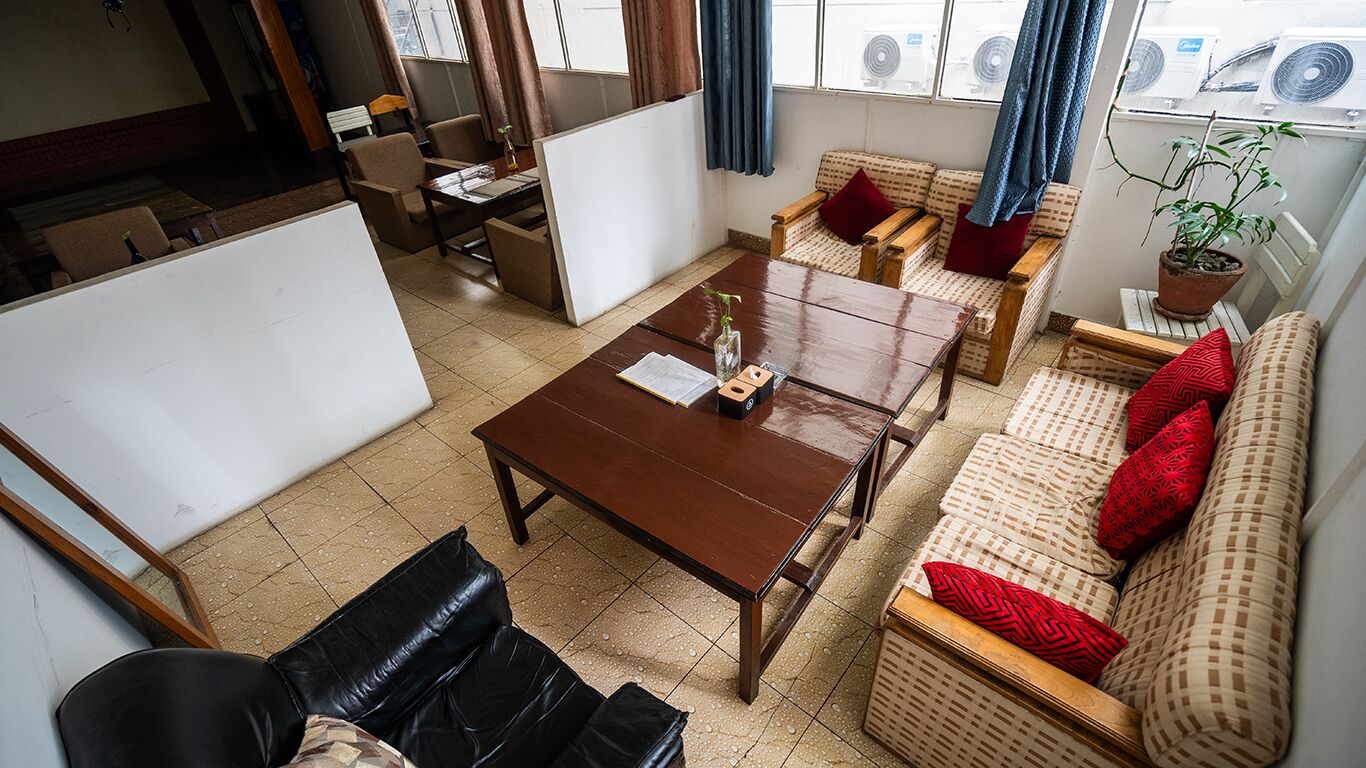 Un salon avec une table basse en bois, un canapé avec des coussins rouges et un fauteuil en osier.