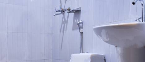 A modern bathroom with a white toilet, a pedestal sink, and a shower with a handheld showerhead.