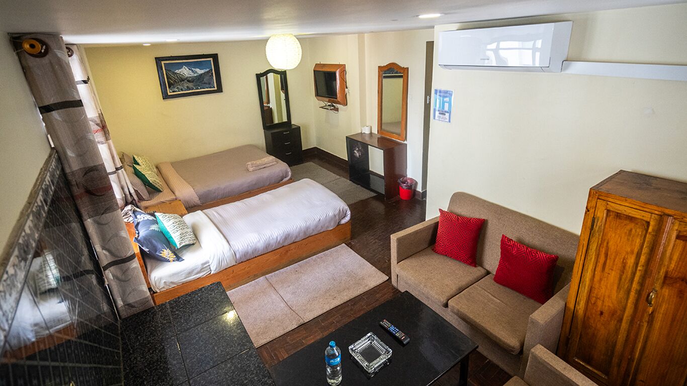 A hotel room with two beds, a sofa, a coffee table, and a TV.
