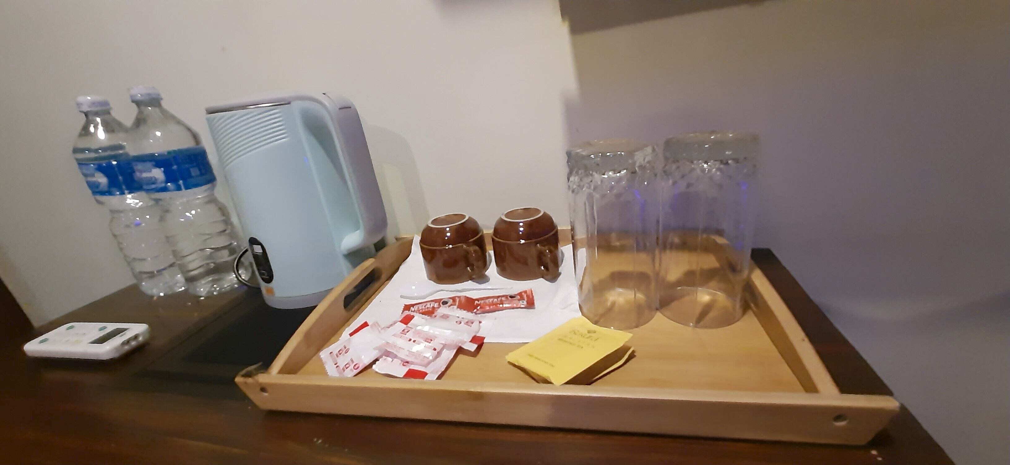 Een dienblad met waterflesjes, een draagbare kachel, bruine mokken en zakjes snacks.