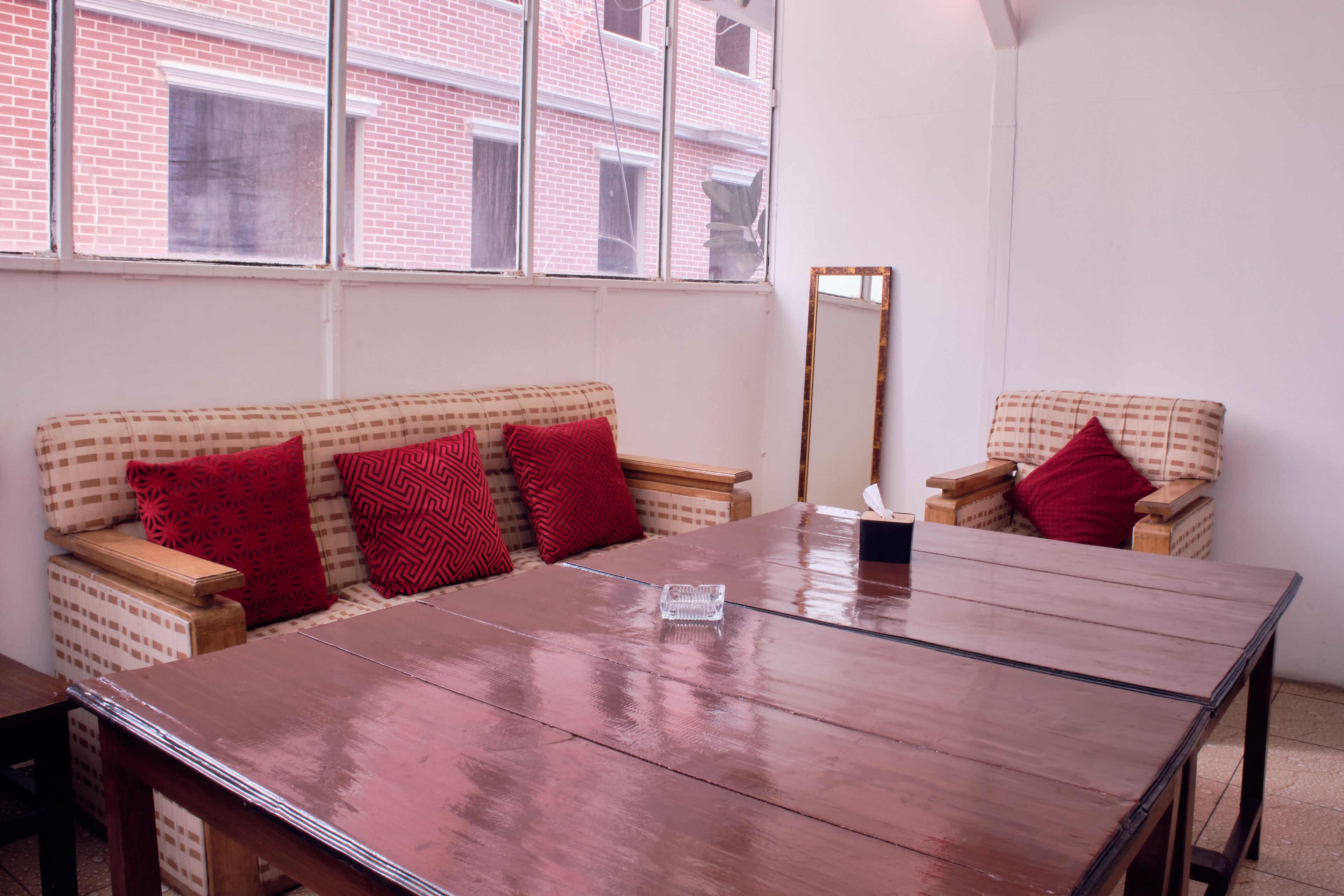 A room with a wooden table, two patterned sofas, and a mirror.
