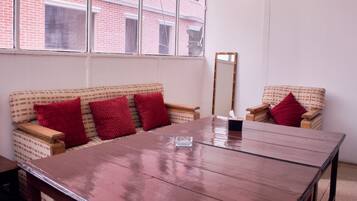 A room with a wooden table, two patterned sofas, and a mirror.