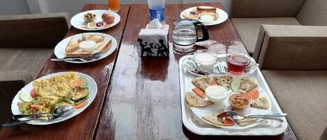 Una mesa de madera dispuesta con diferentes alimentos para el desayuno, como tostadas, huevos y una bebida caliente.