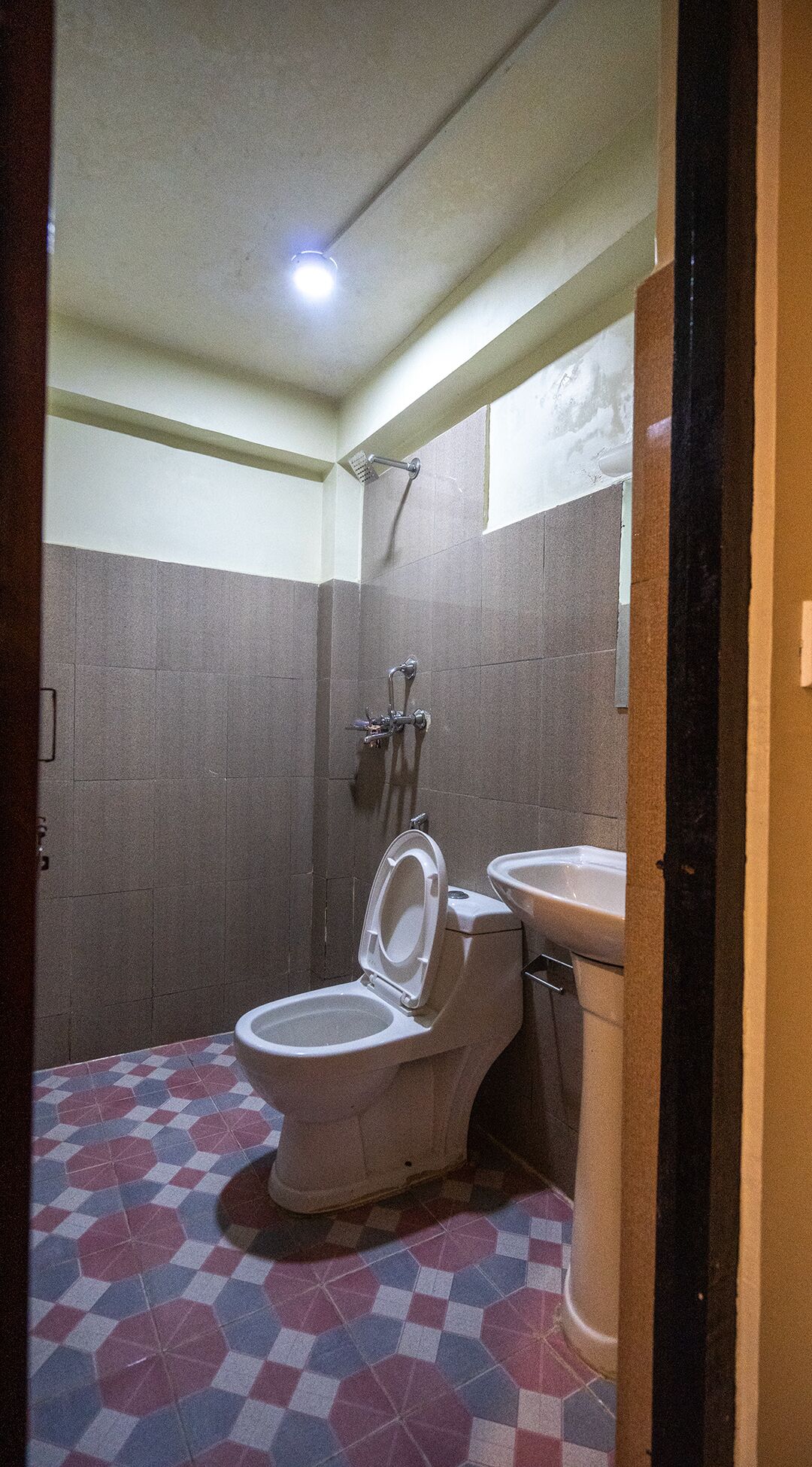 A small bathroom with a toilet, sink, and shower.