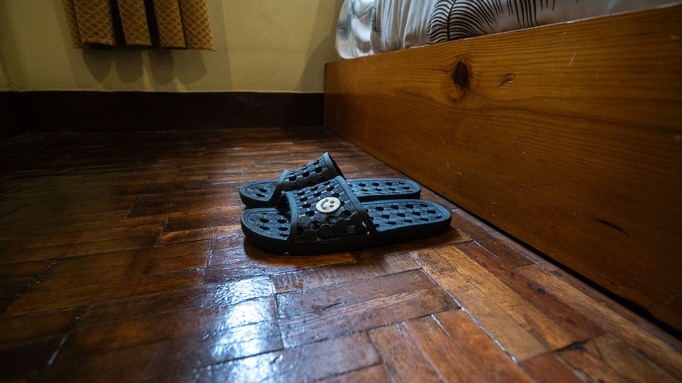 Un par de pantuflas negras con un diseño original sobre un piso de madera.