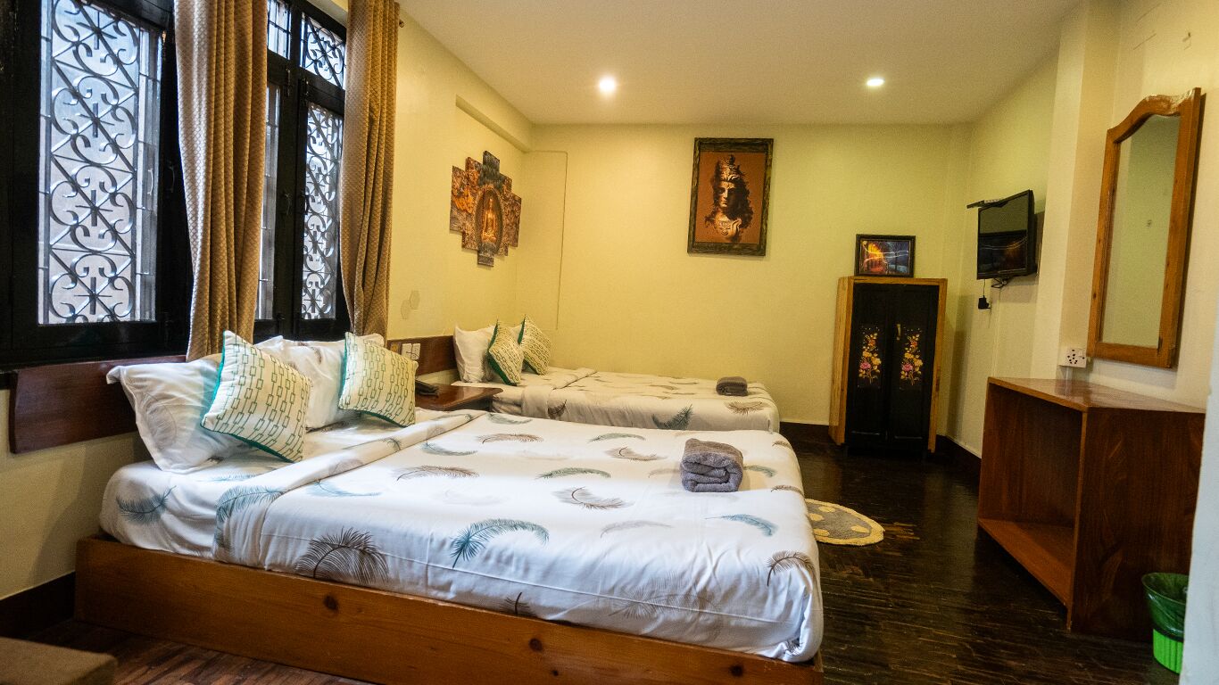 Une chambre avec deux lits, une tête de lit en bois, un miroir et une porte ornée de panneaux de verre décoratifs.