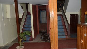 A staircase with a red and blue color scheme, a wooden column, and a potted plant.