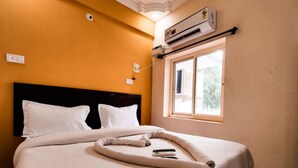 Quarto de hotel com cama, janela e ar condicionado.