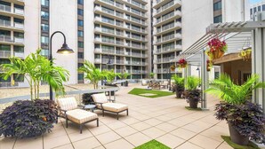 A courtyard with outdoor seating, potted plants, and a building with multiple balconies.