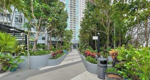 A pathway lined with planters and trees, leading to a building entrance. - Unwind in Your Amazing City View Apartment (Miami)
