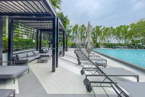 A rooftop pool area with lounge chairs and umbrellas, surrounded by greenery. - Unwind in Your Amazing City View Apartment (Miami)