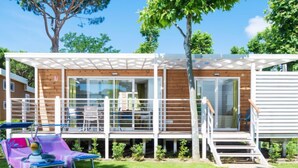 A modern wooden house with a balcony, a small deck, and a slide for children.