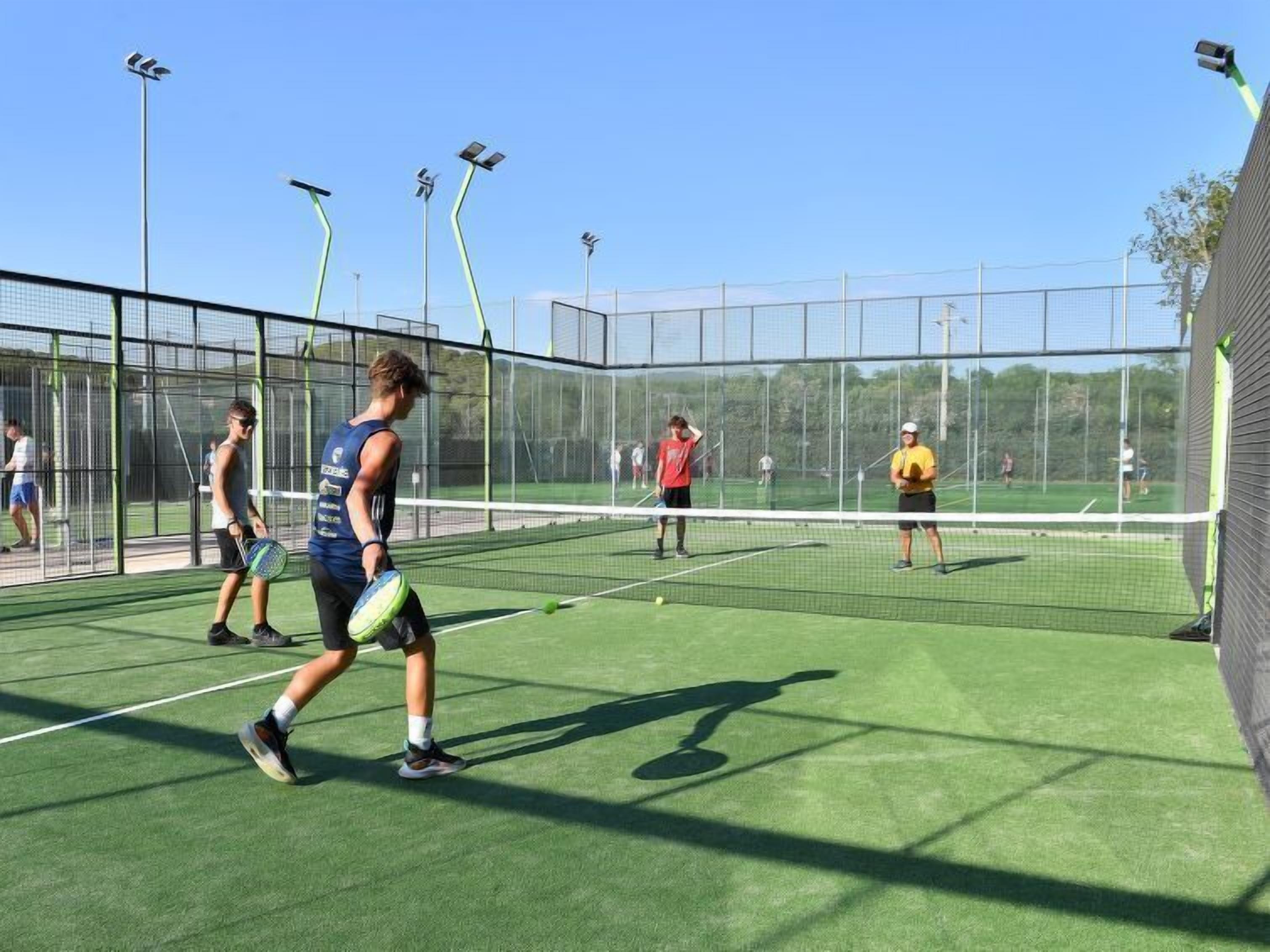 An indoor tennis court with multiple players, a net, and solar-powered lights.