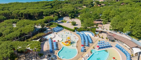 A resort with multiple swimming pools, a water park, and a beach area with umbrellas.