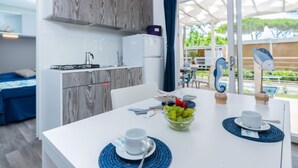 Et moderne køkken med indbygget komfur, et køleskab og et spiseområde med et bord dækket til to personer.