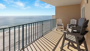 Ein Balkon mit Blick auf Strand und Meer. Zwei Stühle und ein Tisch sind vorhanden.