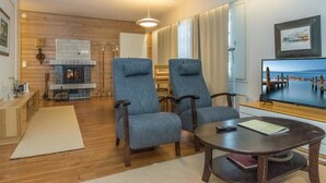A cozy living room with a fireplace, two armchairs, a coffee table, and a television. - Saariseläntie 8 b 7 by Interhome (Inari)