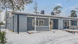 A two-story building with a covered porch and a small deck, surrounded by snow. - Saariseläntie 8 b 7 by Interhome (Inari)